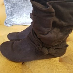 A pair of brown boots with a bow on the sides
